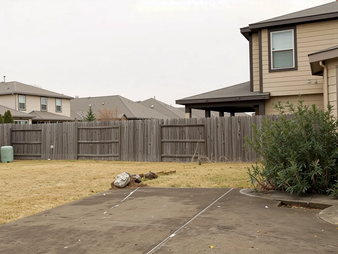 Backyard fence line and patio slab during site preparation in Houston, TX