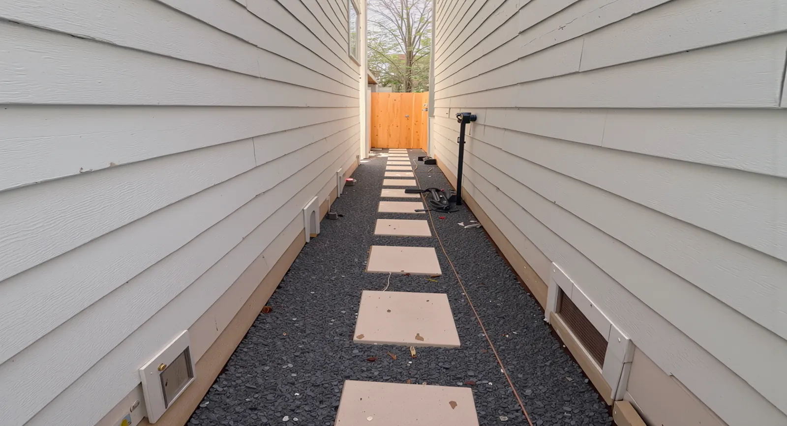 Side yard walkway with stepping stones and gravel between two houses in Houston